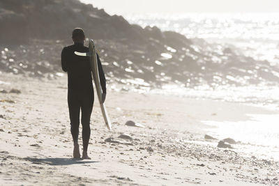 Rear view of man walking at beach