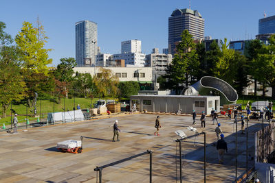 People by buildings in city against sky