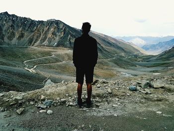 Rear view of man standing on mountain against sky