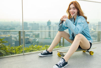 Portrait of a smiling young woman sitting on window