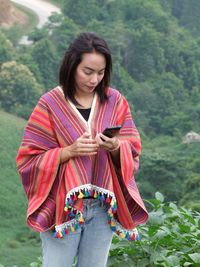 Woman using mobile phone against landscape