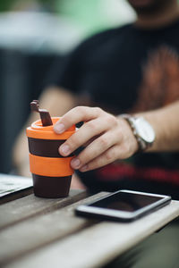 Midsection of man using mobile phone on table