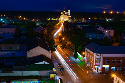 Illuminated street amidst buildings in city at night