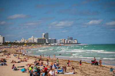 People at beach against sky in city