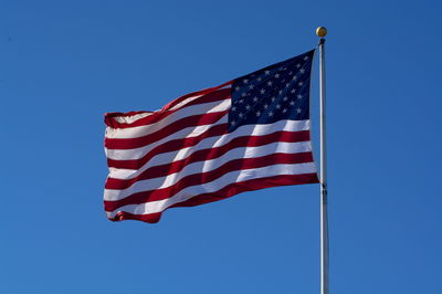 Low angle view of flag against clear blue sky