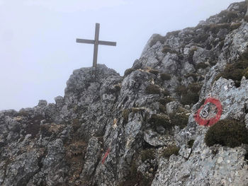 Low angle view of cross on rock against sky