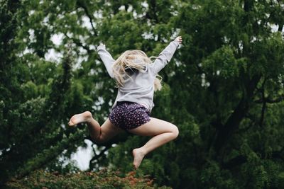 Full length of boy jumping against trees