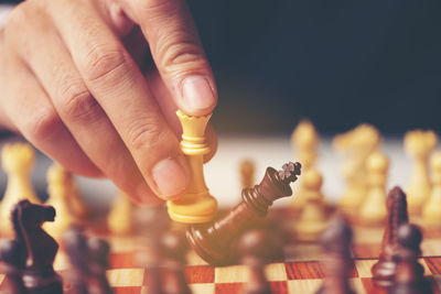 Cropped image of hand playing chess over black background