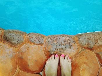 Low section of woman standing at poolside