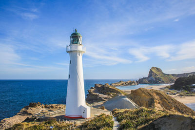 Lighthouse by sea against sky