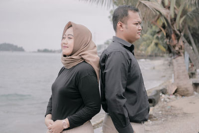 Side view of couple standing on beach