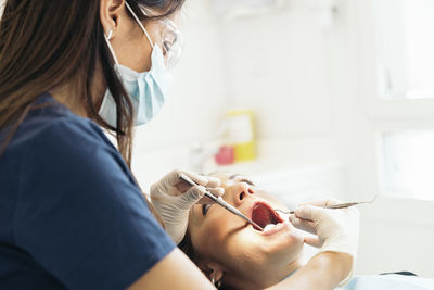 Female dentists examining woman teeth at hospital