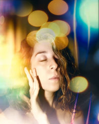 Woman with eyes closed against illuminated lights at night