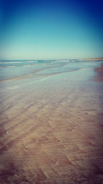 Scenic view of beach against clear blue sky