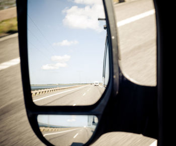 Close-up of side-view mirror against sky