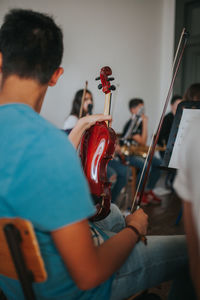 Man holding violin while sitting in classroom