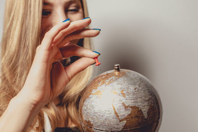 Woman looking at globe against gray background