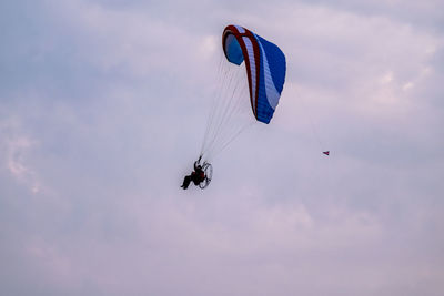 Man paragliding against sky during sunset