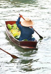 Rear view of woman sitting in boat at lake