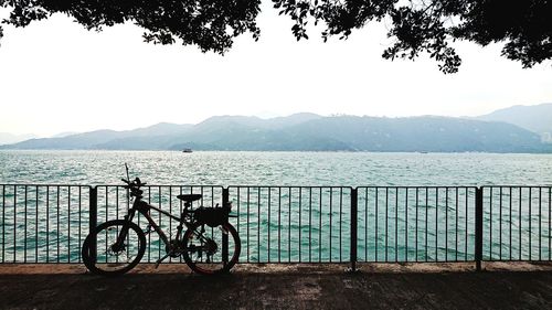 Bicycle by lake against sky