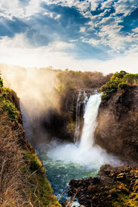 Scenic view of waterfall against sky