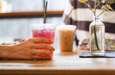 Cropped image of hand holding drink on table