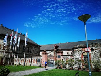 Rear view of man outside house against blue sky