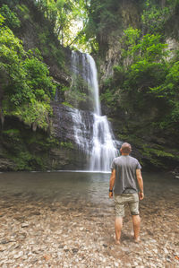 Rear view of man standing against waterfall