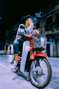 Man smoking cigarette while riding motorcycle on road