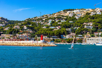 Scenic view of sea by townscape against sky