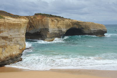 Rock formation on beach against sky