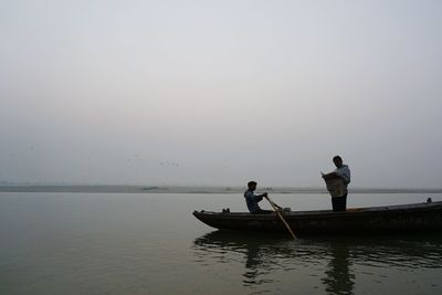 Men in boat on sea against sky