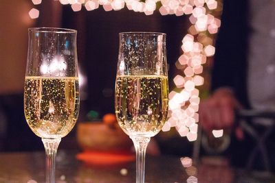 Close-up of champagne flutes on table against illuminated lights