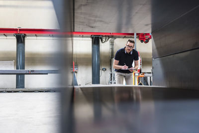 Man writing on clipboard on factory shop floor