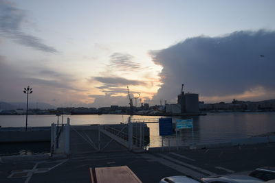 Buildings by sea against sky during sunset
