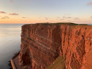 Rock formation on sea against sky during sunset