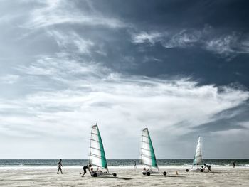 People enjoying at beach with w against sky