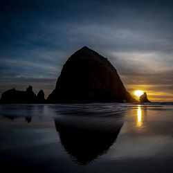 Rock formations in sea against sky during sunset