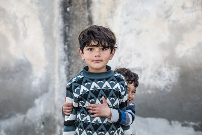 Portrait of boy standing against wall