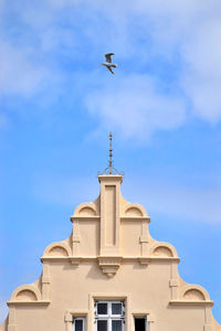 Low angle view of bird flying against building