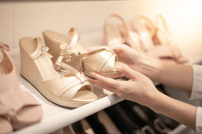 The woman holding shoes in her hands to choose and shopping looking at the shelves footwear.