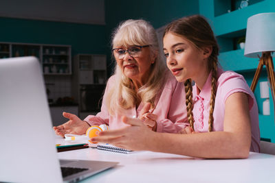 Woman using phone while sitting on table