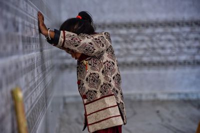 Side view of girl standing by wall