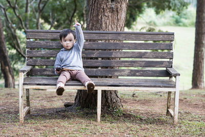 Full length of boy sitting on park bench