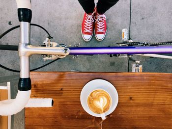 Low section of person holding coffee cup on table