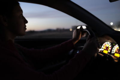 Side view of man driving car against sky