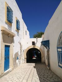 Alley amidst buildings against blue sky