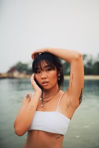 Portrait of young woman wearing bikini standing at beach