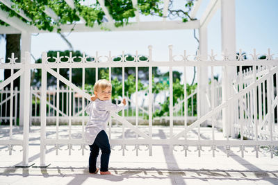 Boy standing by railing against fence
