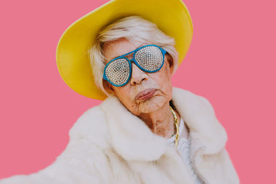 Portrait of woman standing against pink background